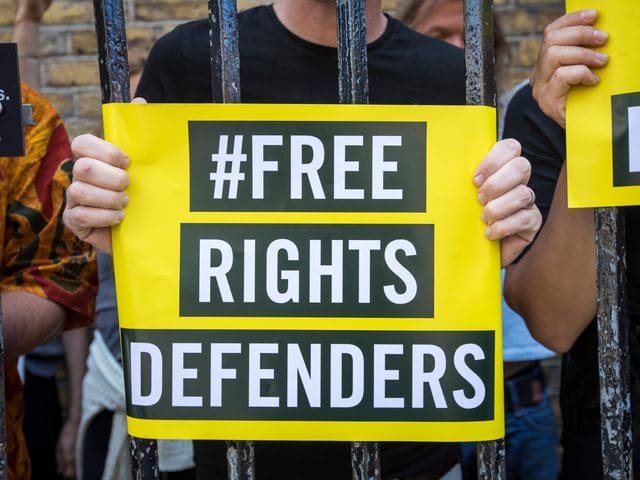 person holding Free rights defenders sign