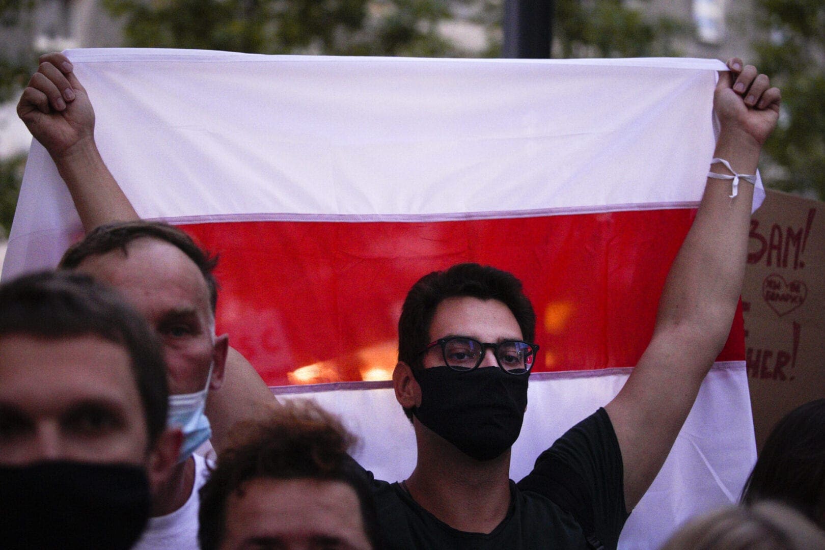 Young man holds flag while wearing a mask