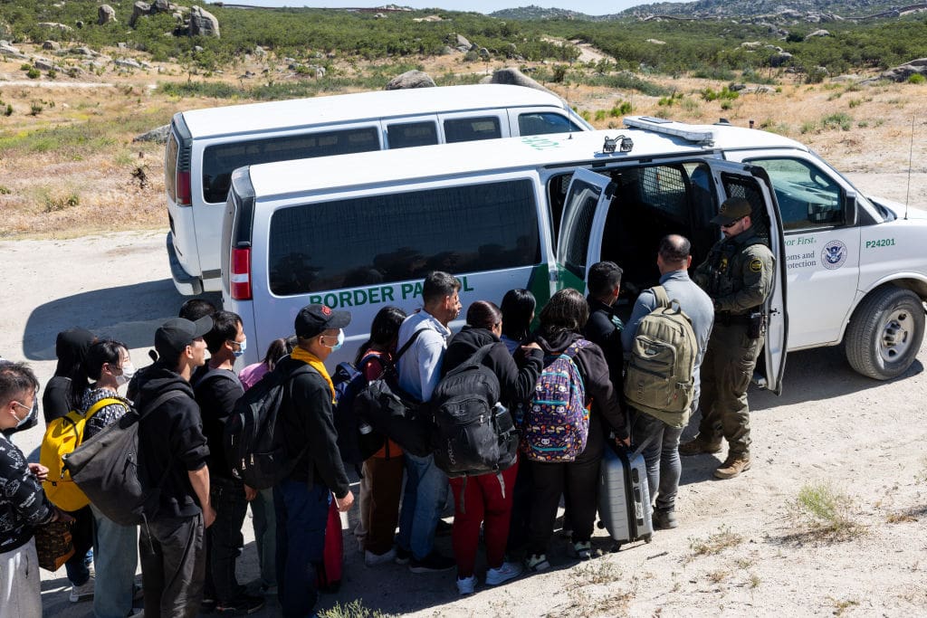 JACUMBA HOT SPRINGS, CA - MAY 26: Migrants get on the patrol vehicle of the U.S. Border Patrol at a new makeshift camp after crossing the US-Mexico border on May 26, 2024 in Jacumba Hot Springs, San Diego, California. (Photo by Qian Weizhong/VCG via Getty Images)