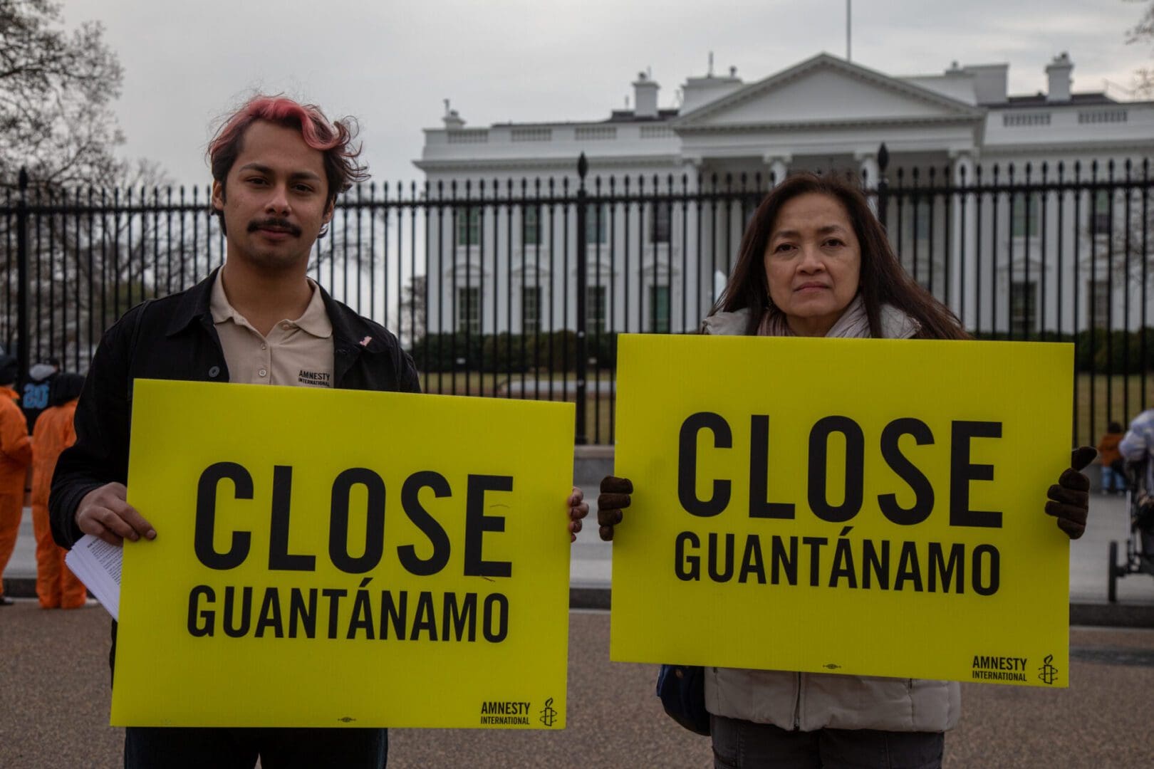 two people holding Amnesty International signs reading Close Guantanamo