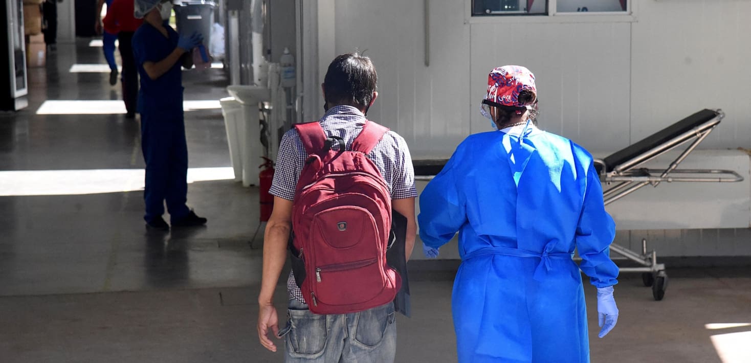 Two people walking in what appears to be health care setting.