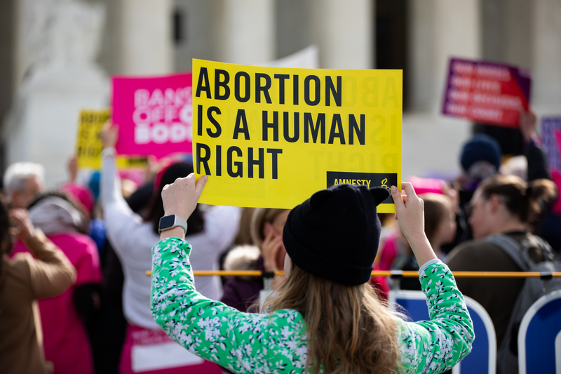 Woman holding an amnesty international sign that reads 