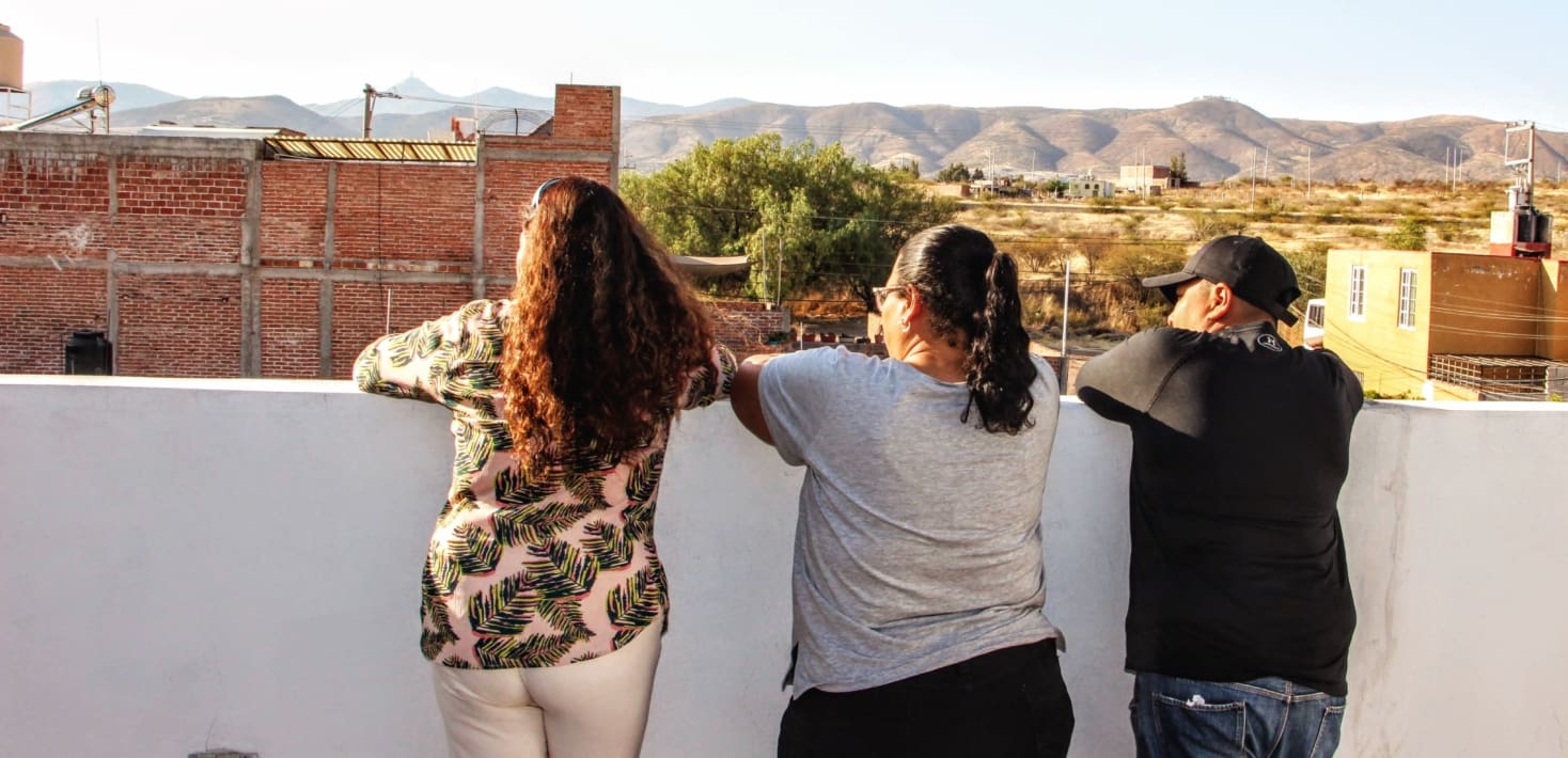 Backs for three people looking over buildings and landscape.