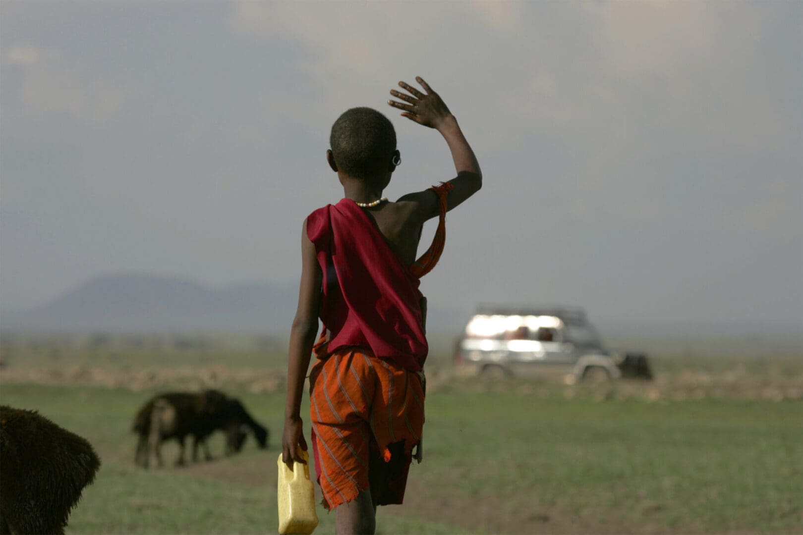 Masai child waves to tourists in Tanzania. Ndutu, Tanzania.