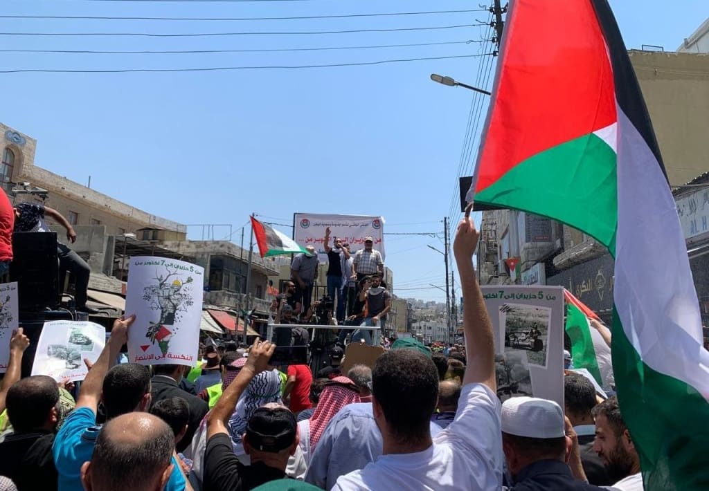 Protestors in street, Jordan, waving Palestinian flag