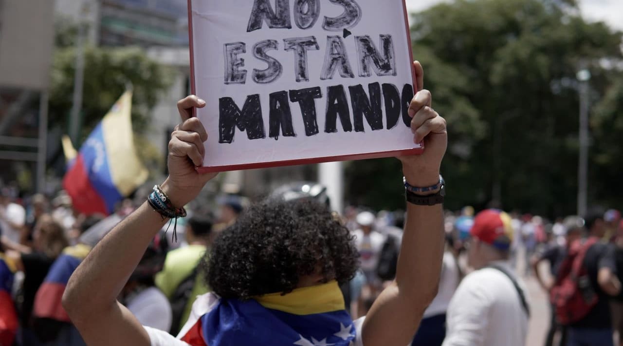 protested in Venezuela holding sign, Nos Estan Matando, which In English is 